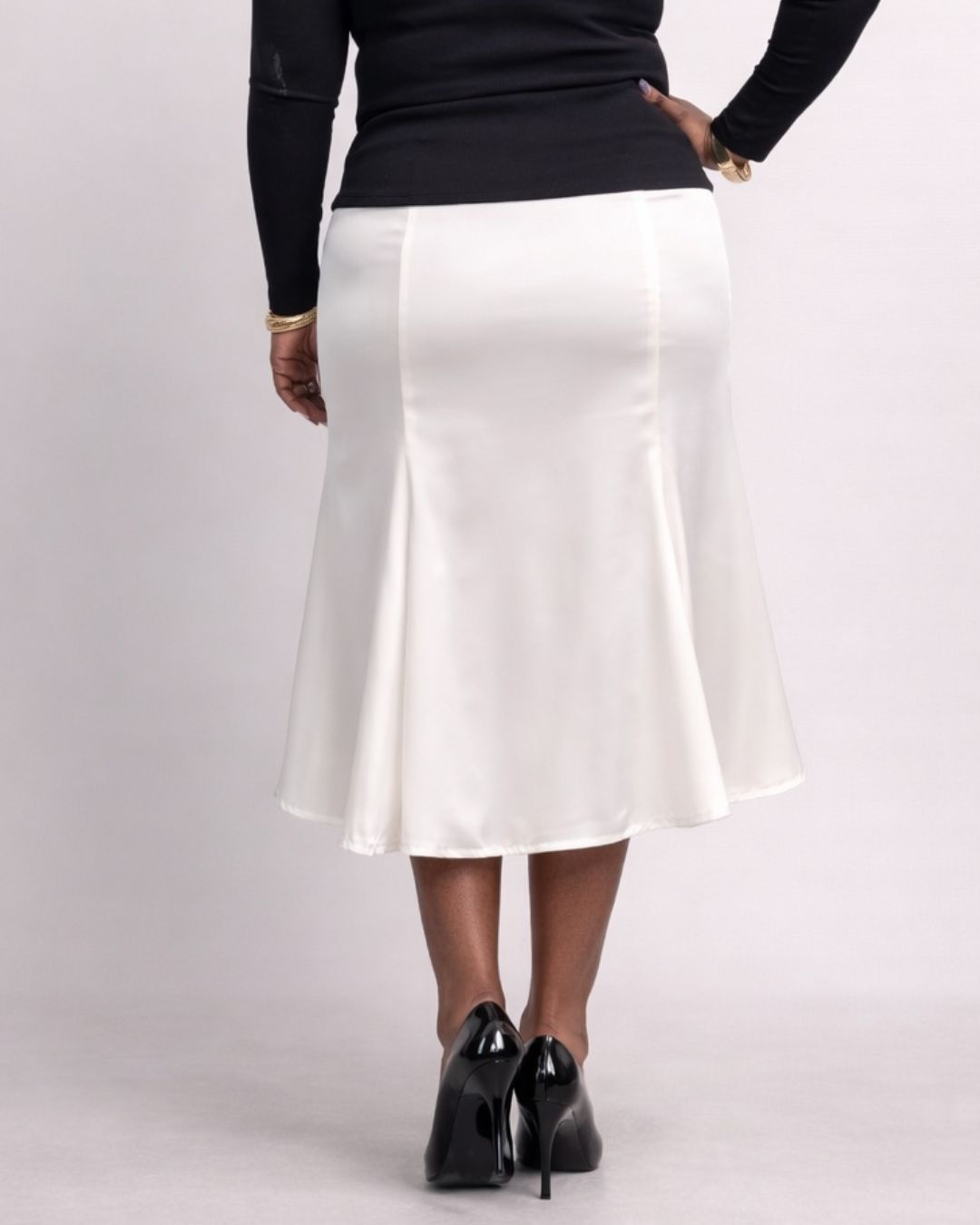 Person wearing a white skirt and black top on a plain background
