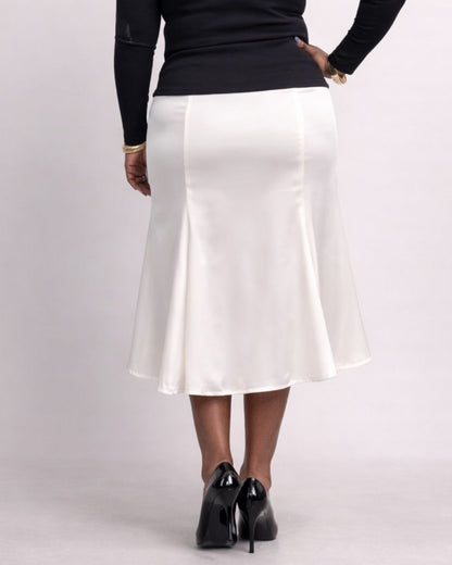 Person wearing a white skirt and black top on a plain background