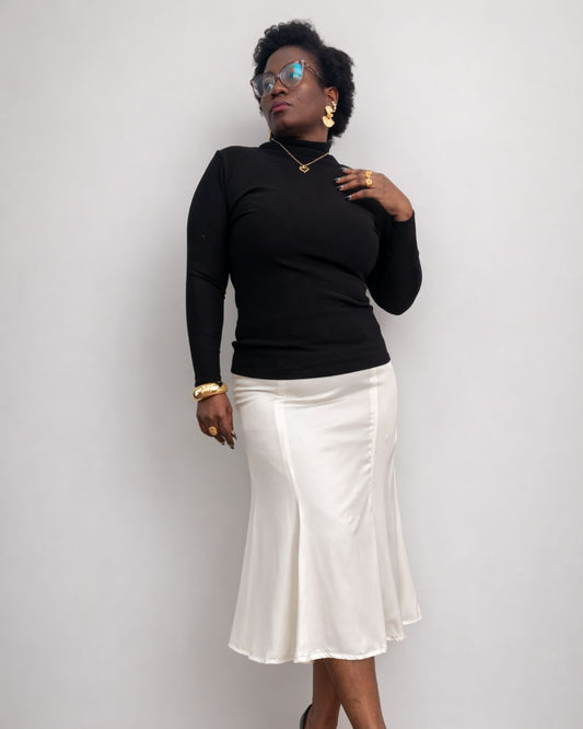 Person wearing a black top and white skirt against a plain background